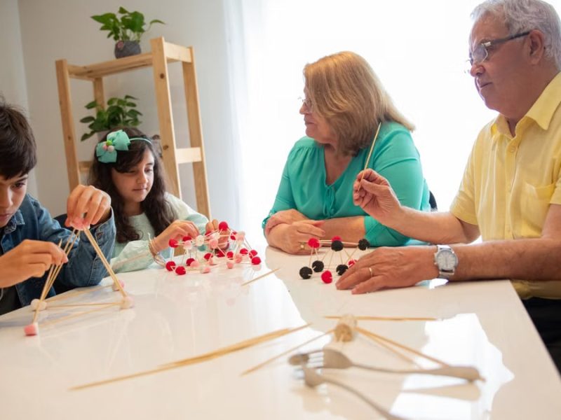 Grandparents and grandchildren engage in a creative building activity indoors.